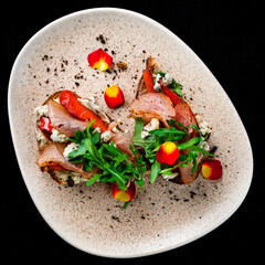 Canvas Print - Bruschettas with bacon, sweet pepper, blue cheese and arugula in a plate.