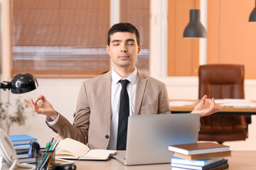 Wall Mural - Young businessman meditating in office. Balance concept