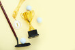 Gold cup with first place medal, golf club and balls on yellow background