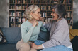© BullRun - Cheerful mature women speaking and sitting together on sofa