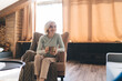 © BullRun - Senior woman sitting in armchair with cup of coffee