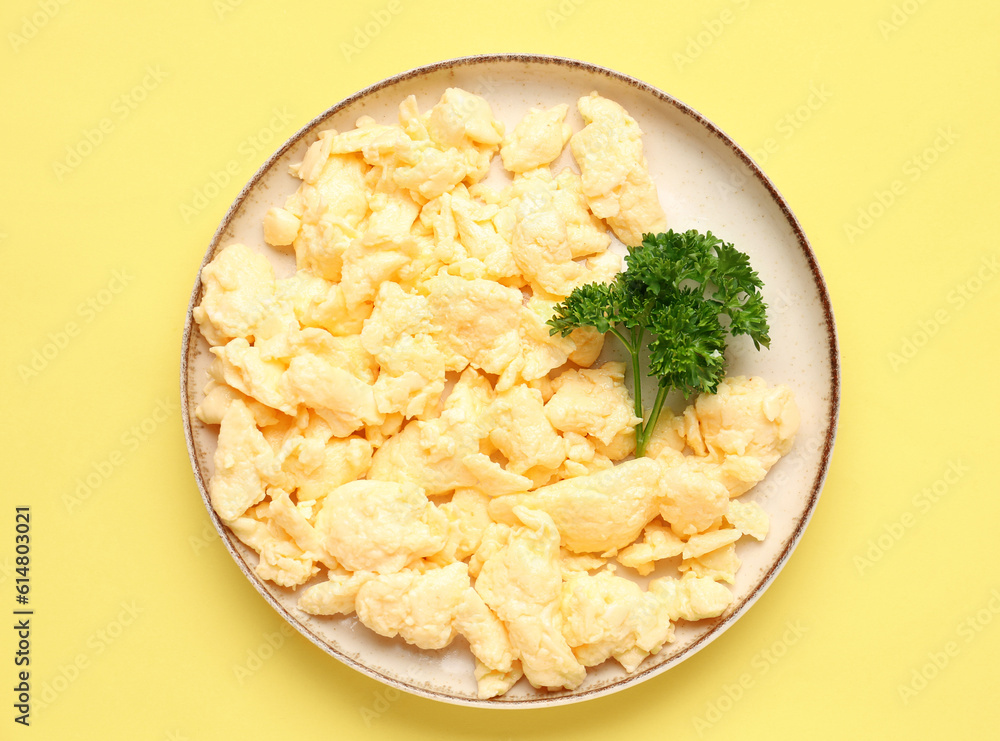 Plate of yummy scrambled eggs on yellow background