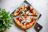 Fototapeta  - Neapolitan pizza Margarita with tomato sauce, mozzarella and basil cooked in the stone oven on a white background