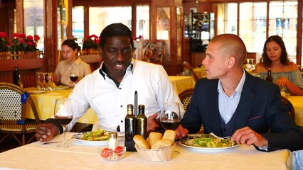 Wall Mural - Two handsome men in classic suits having dinner together at restaurant. High quality 4k footage