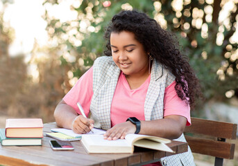 Latin Student Woman Studying Outdoors, Taking Notes While Reading Book