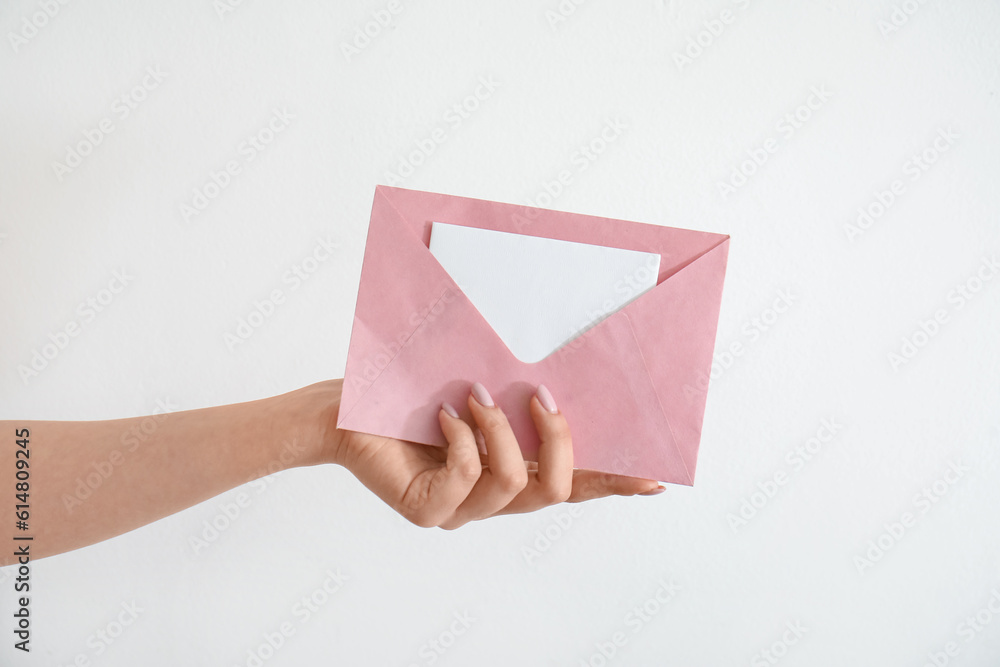 Woman holding envelope with blank invitation card on white background