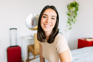 Beautiful young woman smiling standing at home. Joyful portrait of pretty millennial female with toothy smile looking at camera.