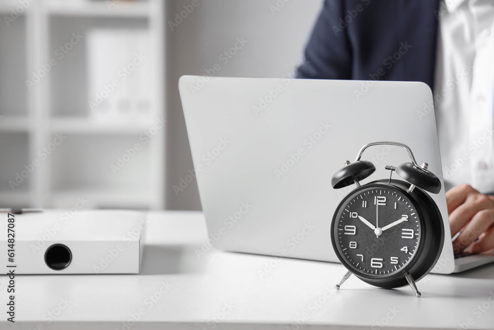 Alarm clock on table of working businessman in office, closeup