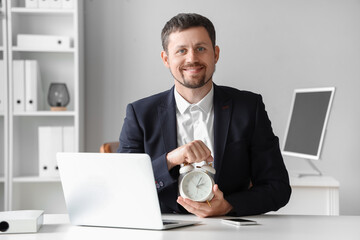 Young businessman with alarm clock in office