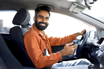 Wall Mural - Happy Indian Driver Man Using Mobile Phone Sitting In Automobile