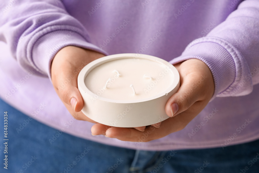 Young woman holding white candle, closeup