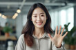 © JuanM - Close up of a woman at work smiling at her workplace and giving a high five to the camera. Generative AI
