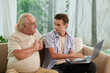© DragonImages - Young man showing grandfather website he created