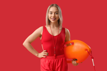 Wall Mural - Female lifeguard with rescue buoy on red background