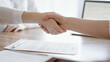 © rogerphoto - Business people shaking hands above contract papers just signed on the wooden table, close up. Lawyers at meeting. Teamwork, partnership, success concept