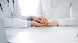 © rogerphoto - Doctor and patient sitting near each other at the table in clinic office. The focus is on female physician's hands reassuring woman, only hands, close up. Medicine concept