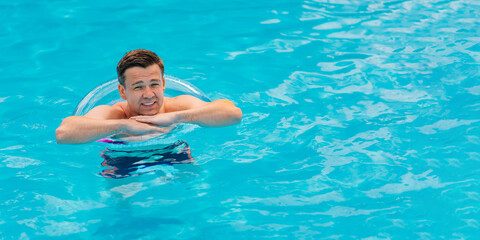 Wall Mural - Portrait of a cheerful middle-aged man in the pool with inflatable lifebuoy.