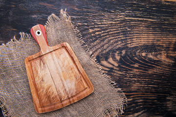 Wall Mural - Empty cutting board and burlap on a dark wooden table. View from above. copyspace.