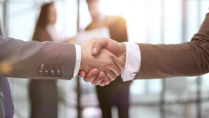 Wall Mural - Close-up of business partners shaking hands after a successful agreement against the background of colleagues