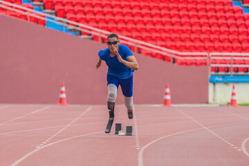 Wall Mural - Asian male athlete, prosthetics user, sprints off from block start, powering his practice run on stadium track