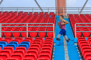 Wall Mural - Asian male athlete with prosthetics, exercises by jogging in stadium bleachers aisle