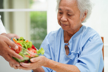 Wall Mural - Asian elderly woman patient eating salmon stake and vegetable salad for healthy food in hospital.