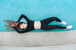 © Ilia K - Woman with a sporty figure is lying on a sports field. Fitness training to maintain a beautiful figure.