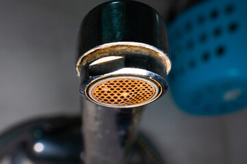 aerator diffuser in the faucet close-up. Corrosion and scale deposits from water. Dirty old water faucet in the washbasin on a blurred background