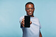 © Flamingo Images - African man holding up his blank phone screen