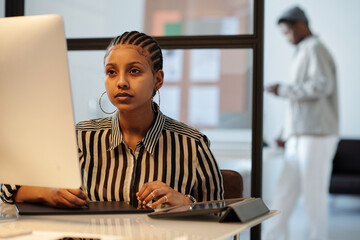 Aufkleber - Serious young black woman looking at computer screen while drawing graphic sketches with stylus on touchpad in office environment