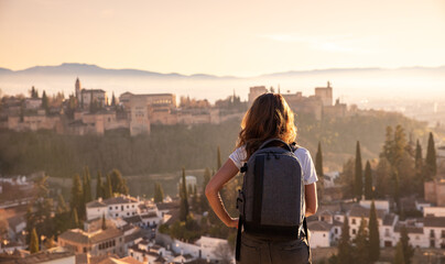 Wall Mural - rear view of woman enjoying sunset over granada city landscape- spain