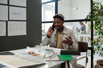 Aufkleber - Young successful architect with smartphone by ear taking phone consultation of colleague while sitting by workplace in office