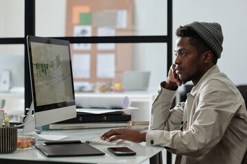Aufkleber - Young serious male architect or designer looking at graphic sketches on computer screen while working over new architectural project