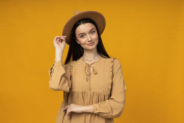 Wall Mural - Young woman in a hat on a yellow background