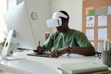 Aufkleber - Young male designer in virtual reality headset drawing graphic sketches on touchpad with stylus while sitting in front of computer screen