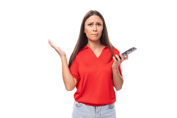 Wall Mural - Pretty caucasian woman with black hair is wearing a red blouse with a halter neckline and is holding a phone