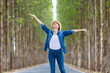 © Akarawut - Asian tourist woman is jumping and dancing while having vacation at the national park while walking on the road with column of tree for travel and adventure