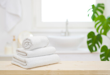 Wall Mural - white folded towels on wooden table top in blurred bathroom