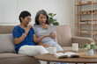 © itchaznong - Asian elderly women and friend using social media and living room. Video streaming, happiness and conversation at a house with old people together