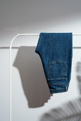 Wall Mural - Jeans displayed on clothes rack with shadows on white background