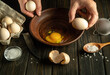 © Віталій Б. - The cook on the kitchen table prepares eggs for a fire or an omelette. Close-up of a chef hand holding an egg