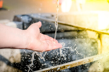 Girl's hands and flowing water at the water fountain in town