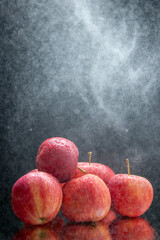 Wall Mural - Vertical view of stacked fresh red apples on light on dark wave background