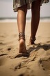Hippie female feet with ankle jewellery in the sand on a beach.