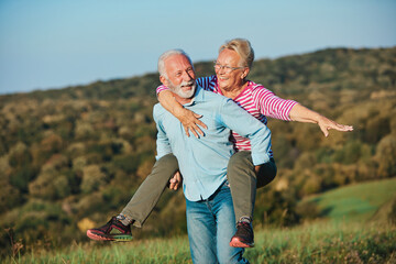 Wall Mural - woman man outdoor senior couple happy lifestyle retirement together smiling love piggyback active ma