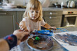 Father helping little girl painting with tempera paint using a paintbrush.