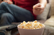 Caucasian man sitting on sofa with popcorn and tv remote
