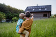 © Halfpoint - Rear view of father and his son looking at their house with solar panels on the roof.