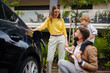 © Halfpoint - Happy family standing beside their car and charging electric car on the street.
