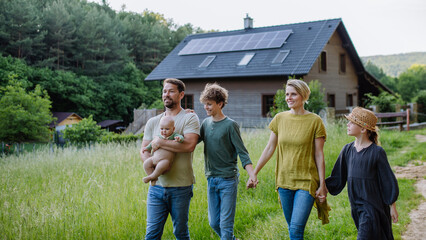 Wall Mural - Happy family near their house with solar panels. Alternative energy, saving resources and sustainable lifestyle concept.